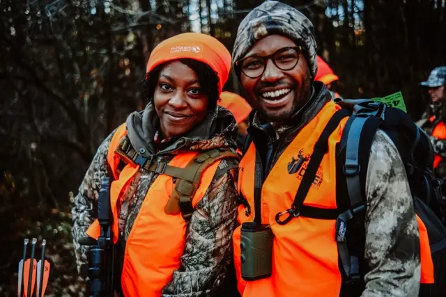 HOC members in the field wearing an orange vest holding bow and arrows.