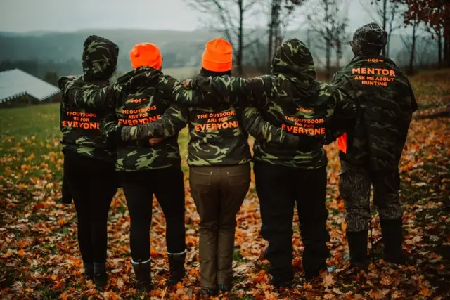 HOC members in the field wearing a sweater with the mentor on the back.