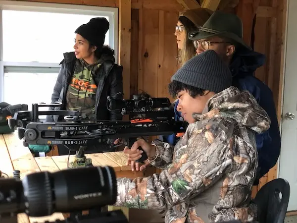 HOC member with crossbow in shed.
